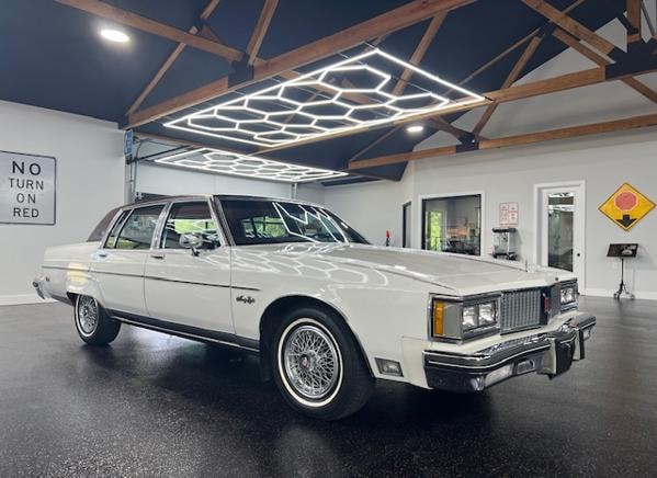 1982 Oldsmobile 98 — white with brown vinyl roof in modern garage