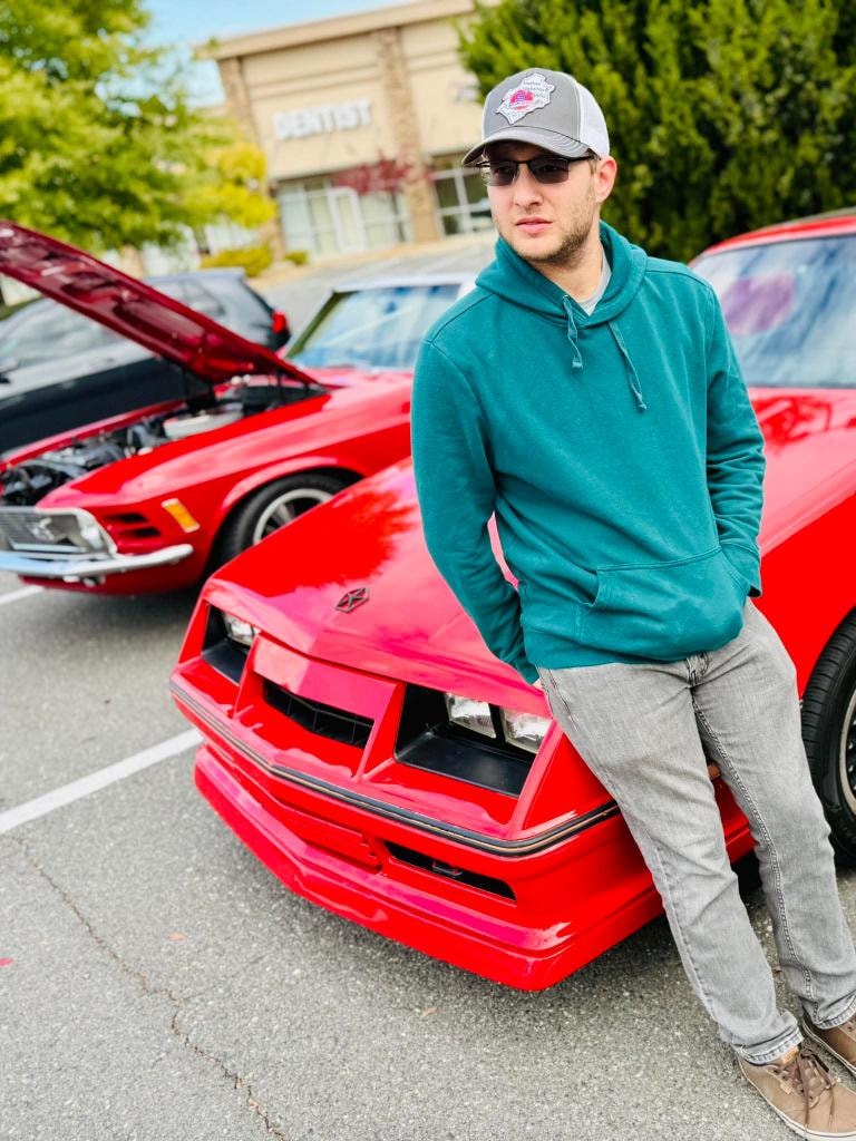 Owner leaning on his 1986 Dodge Daytona Turbo Z at a car show